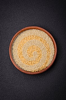 Raw risoni pasta made from durum wheat on a dark concrete background