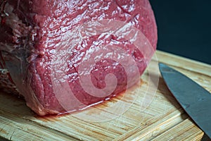 raw roast beef meat on wooden cutting board closeup