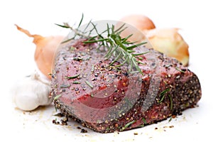 Raw roast beef with rosemary, onion and garlic