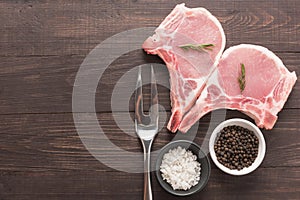 Raw roast meat and meat fork on wooden background
