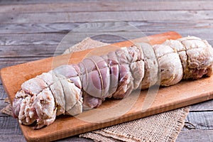 Raw roasted pork roll stuffed with vegetables and garlic