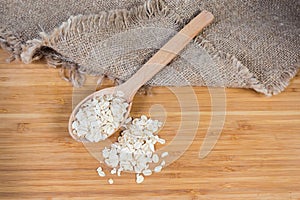 Raw rolled oats in wooden spoon and scattered beside