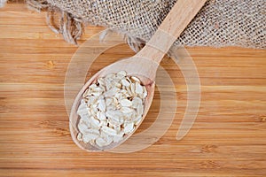 Raw rolled oats in wooden spoon, top view close-up