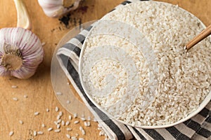 Raw round white rice in a bowl close-up on a wooden background. Healthy food.