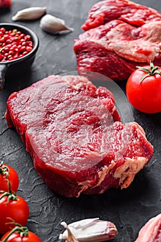 Raw rump  beef steak cuts, with herbs, seasoning  on black table, side view