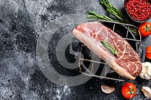 Raw rump cap steak on a grill. Black background. Top view. Copy space