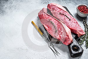 Raw rump or picanha steak on a wooden cutting board. White background. Top view. Copy space