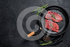 Raw rump steak in a frying pan. Beef meat. Black background. Top view. Space for text