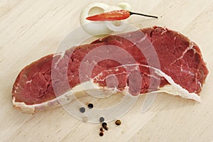 Raw rump steak and pepper corns on chopping board