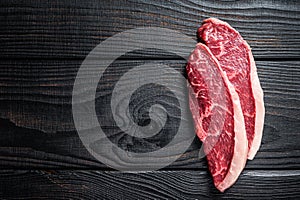 Raw rump steak or top sirloin cap beef meat steaks on butcher table. Black wooden background. Top view. Copy space