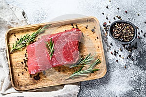 Raw rump steak on a wooden tray. Beef meat. Gray background. Top view