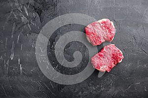 Raw rump steaks over black background, top view with space for text