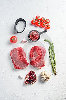 Raw rumpsteak, farm beef meat with seasonings, rosemary, garlic. White textured background. Top view