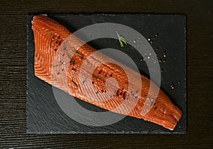 Raw salmon filet on dark slate background, wild atlantic fish