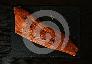 Raw salmon filet on dark slate background, wild atlantic fish