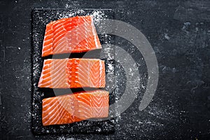 Raw salmon filet on dark slate background, wild atlantic fish, space for text