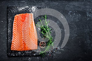 Raw salmon filet on dark slate background, wild atlantic fish, space for text