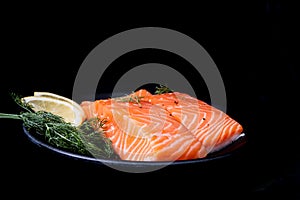Raw salmon filet with rosemary and lime on dark background, wild Atlantic fish. Delicious fish meat. side view