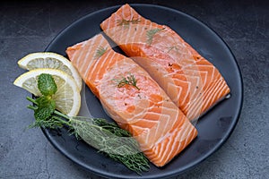 Raw salmon filet with rosemary and lime on dark slate background, wild Atlantic fish. Delicious fish meat. top view