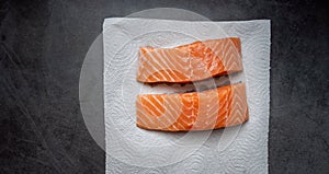 Raw salmon filet with white paper on dark slate background, wild Atlantic fish. Delicious fish meat. top view