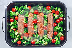 Raw salmon fillet with broccoli and tomato on frying tray, ready to bake, horizontal, top view