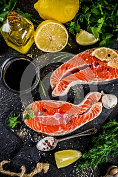 Raw salmon fish steaks with lemon, herbs, olive oil, ready for g