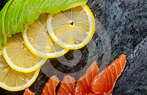 Raw salmon with lemon and avocado on marble plate background