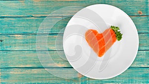 Raw salmon slice in shape of heart on white plate