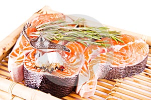 Raw salmon steak with rosemary on a bamboo board