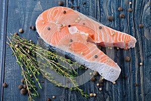 Raw salmon with thyme and pepper on a wooden board. close-up