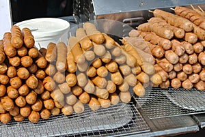 Raw sausage are pecked with skewers and ready to be grill.