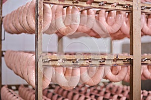 Raw sausages on racks in storage room at meat processing factory