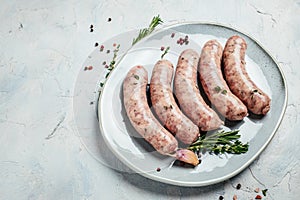 Raw sausages with spices and rosemary on plate. Cooking ingredients. Natural healthy food concept. Long banner format. top view