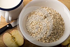 Raw scottish oatmeal, milk in a mug and apple