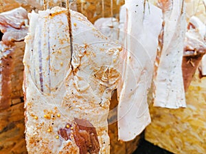 Raw seasoned pork meat hanged for the smoking process