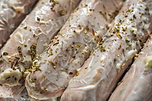 Raw seasoned sausages on baking tray closeup