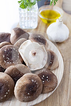 Raw shiitake mushrooms in the kitchen with parsley, olive oil and garlic. Mushroom photography.