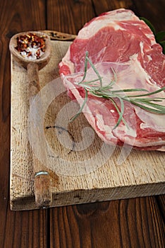 Raw shoulder lamb on wooden board and table