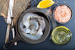 Raw shrimp in a frying pan top view on a black background
