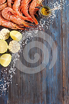 Raw shrimp, garlic, lime, curry and sea salt on a dark wooden background