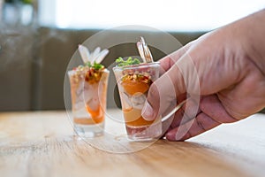 Raw shrimp and salmon with seafood sauce in shot glass is a cocktail