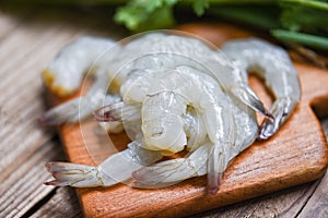 Raw shrimp on wooden cutting board background for cooking / close up fresh shrimps or prawns Seafood shelfish