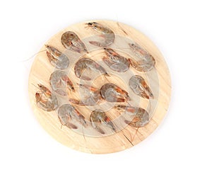 Raw shrimp on wooden platter.