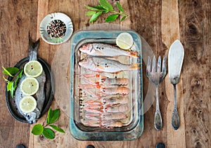 Raw shrimps  and red mullets on metal plate. Fresh seafood metal plate on stone table. Snack, appetizer. Fresh dorada fish