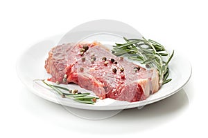 Raw sirloin steak with rosemary and spices on plate