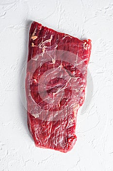 Raw skirt or flank steak,on a white stone background top view vertical photo