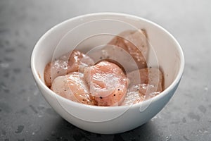 Raw sliced chicken fillet meat in spices marinating in bowl