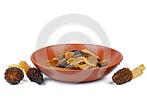 Raw sliced morel mushrooms in the clay plate isolated on white