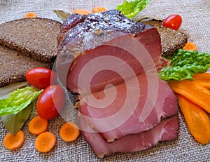 Raw smoked meat cooked according to old, traditional recipes, along with bread and vegetables photo