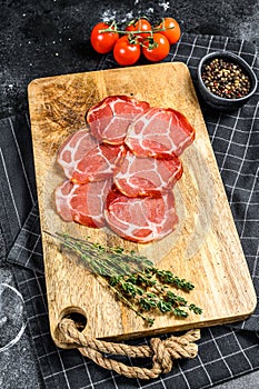 Raw smoked meat Jamon Lomo. Black background. Top view photo